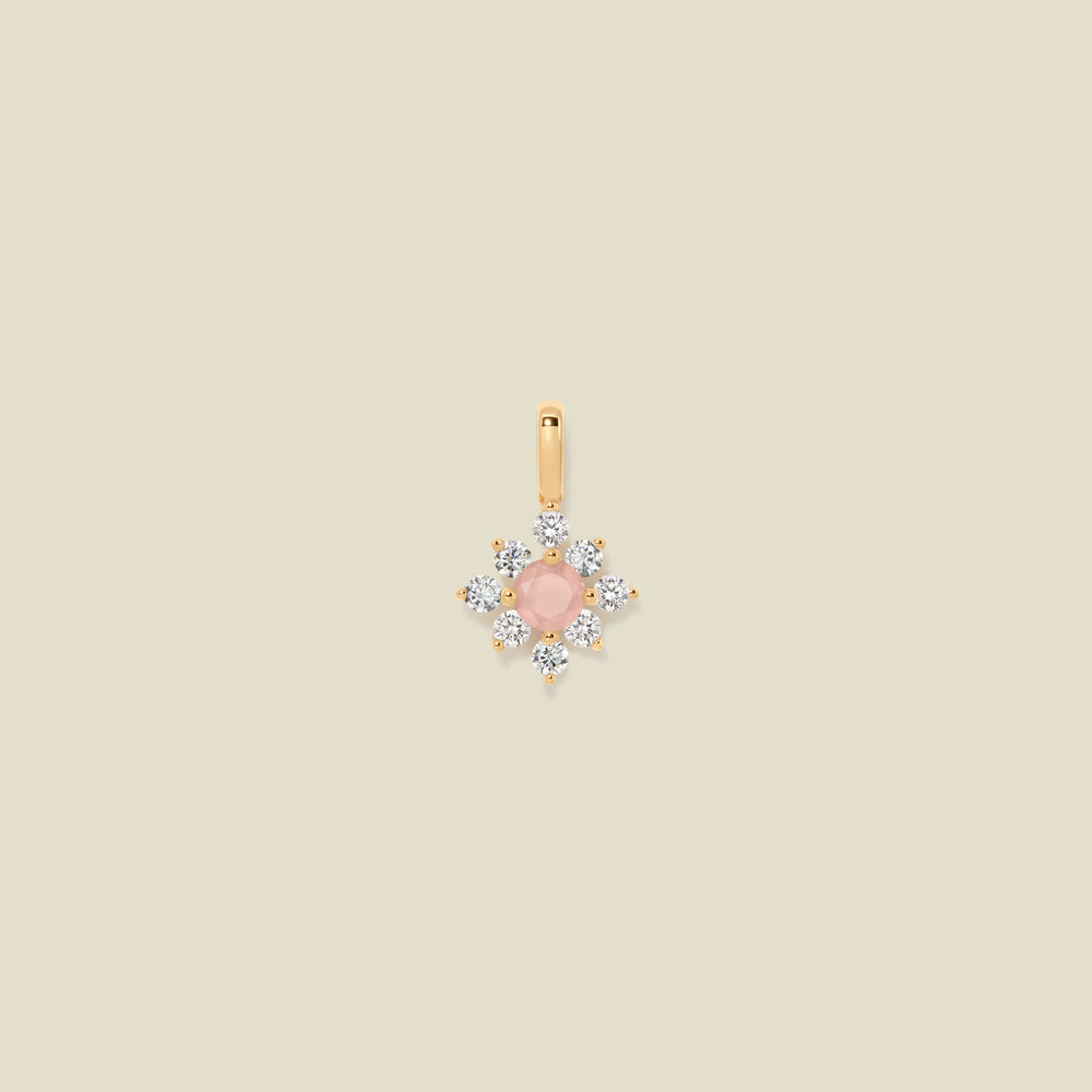 Gold charm with prong-set pink and clear stones against a neutral background.
