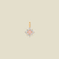 Gold charm with prong-set pink and clear stones against a neutral background.