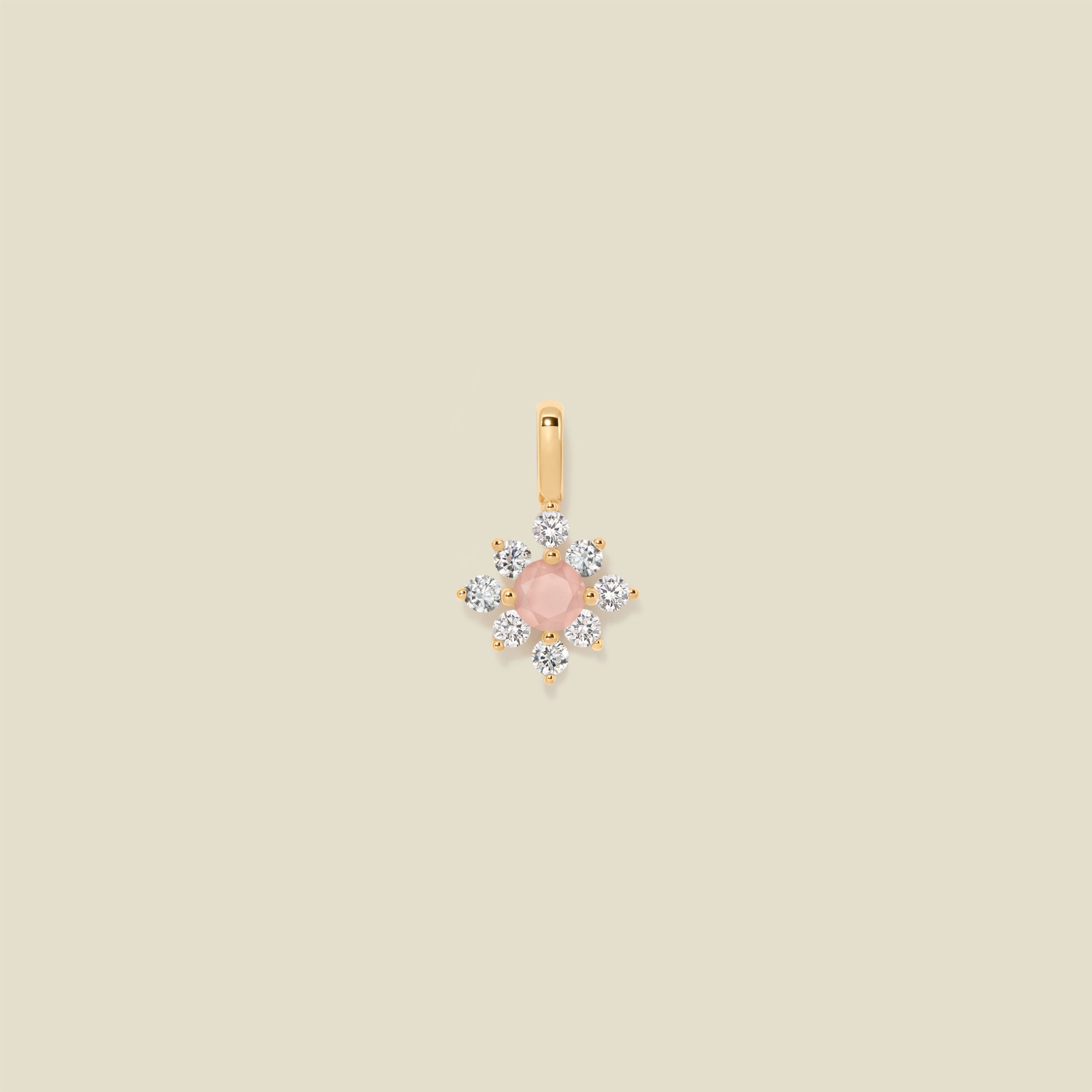 Gold charm with prong-set pink and clear stones against a neutral background.