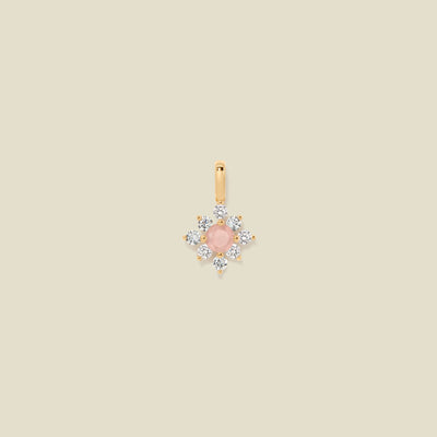Gold charm with prong-set pink and clear stones against a neutral background.