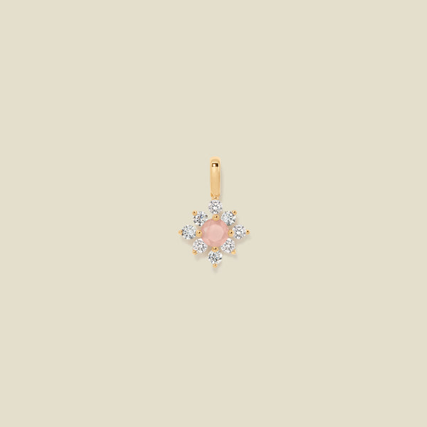 Gold charm with prong-set pink and clear stones against a neutral background.