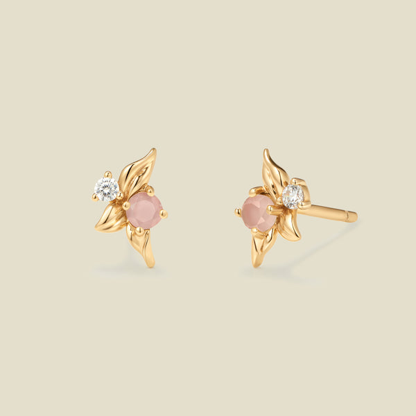 Gold stud earrings with prong set pink and clear stones against a neutral backdrop.