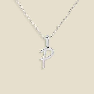 A silver initial pendant necklace featuring the uppercase letter 'P' on a delicate silver chain, set against a solid light beige background.