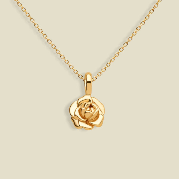 A gold necklace with a peony-shaped pendant, displayed against a solid light beige background.