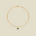 A thin gold wire hoop necklace with a small oval blue-green gemstone pendant, displayed on a solid light beige background.