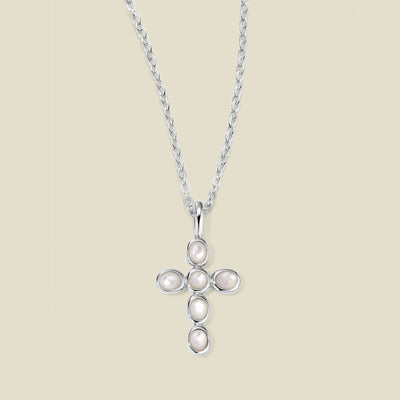 Silver necklace with a cross pendant made of bezel-set pearl stones against a neutral background.