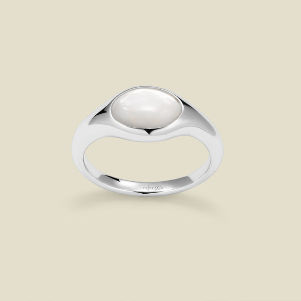 Silver ring with a bezel-set pearl stone against a neutral background.