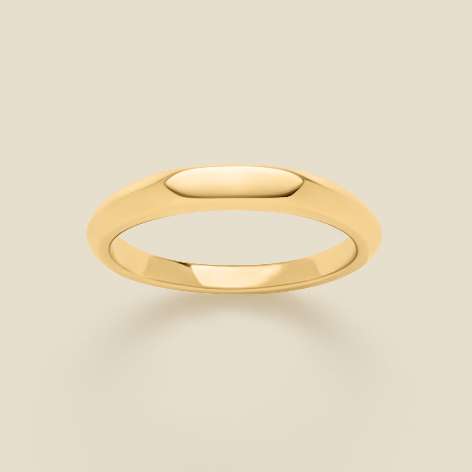 Gold signet ring on a beige background
