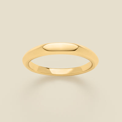 Gold signet ring on a beige background