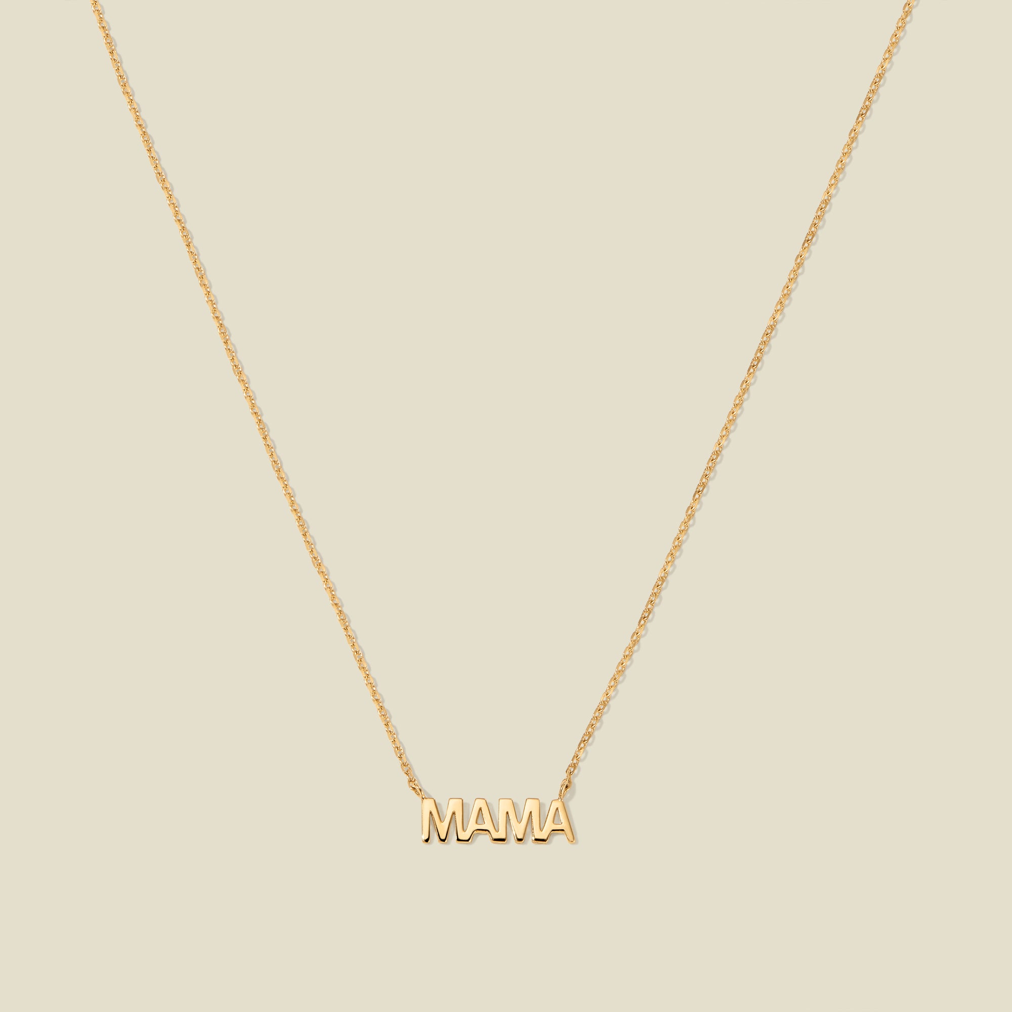 Gold “MAMA” letter necklace with delicate chain on a beige background
