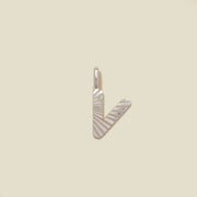 A small silver V-shaped charm with a textured, sunburst striped pattern, shown on a solid light beige background.