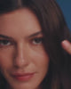 A lifestyle video of a dark haired woman set against a royal blue backdrop showing off multiple different colored gemstone rings, and necklace charms.