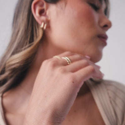A short video showing close-ups of a person's hands wearing multiple stacked gold eternity rings, each with a different color of square cut gemstones in a single continuous row.