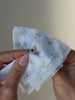 A video featuring a gold signet ring featuring a dark blue stone surrounded by clear cz stones being held in tissue paper, then being placed onto a hand with multiple other gold rings stacked.