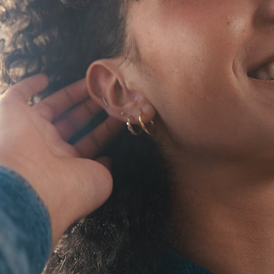 A short close-up lifestyle video of a woman showing off her ear with multiple earrings of varying shapes and sizes.